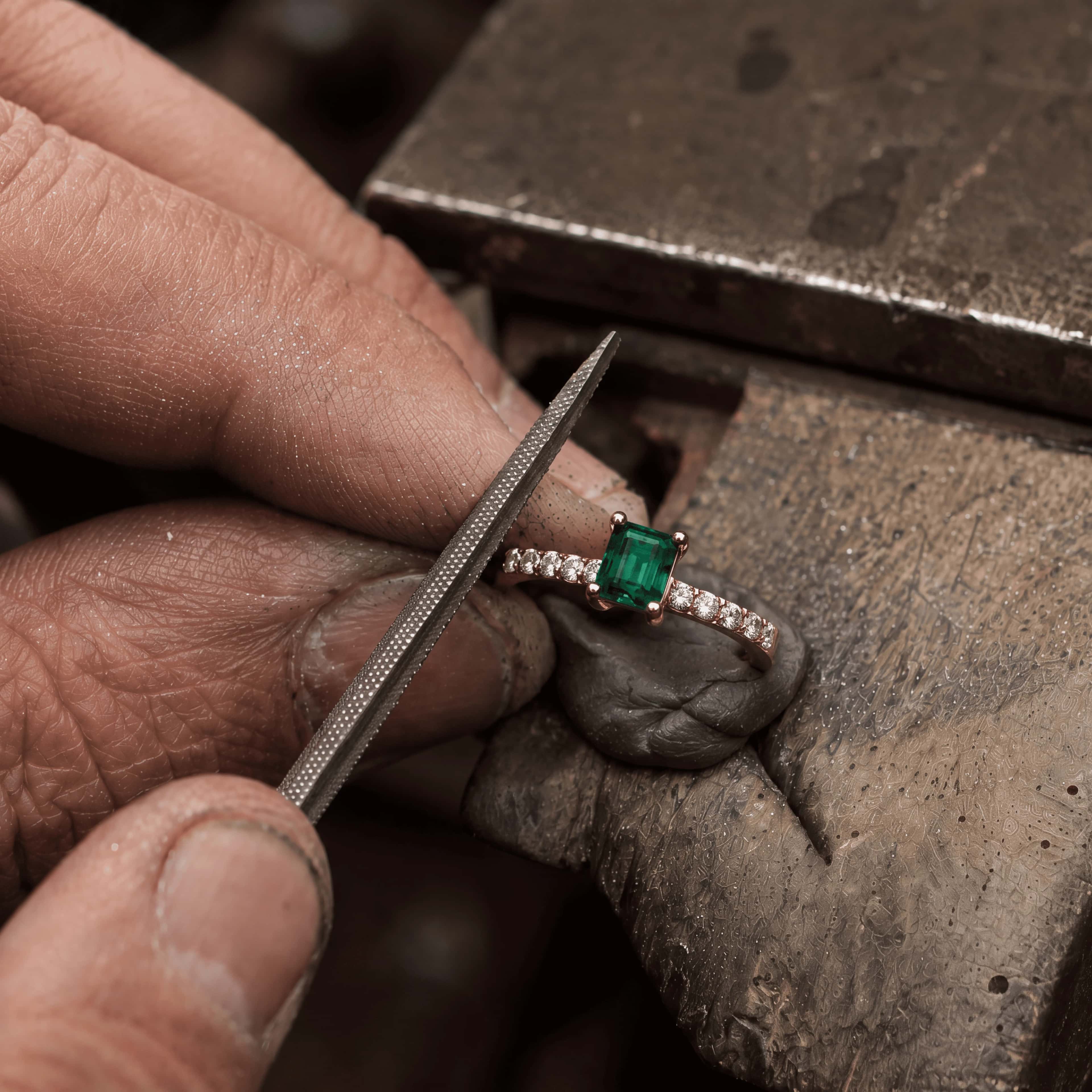 Jeweller finishing an emerald and diamond ring at the bench